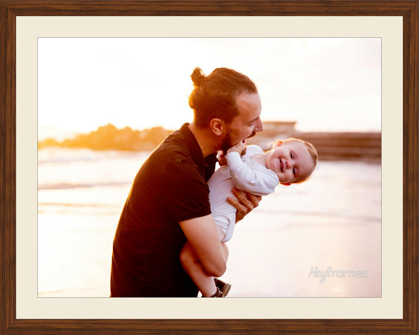 A father lifting his laughing baby at golden hour