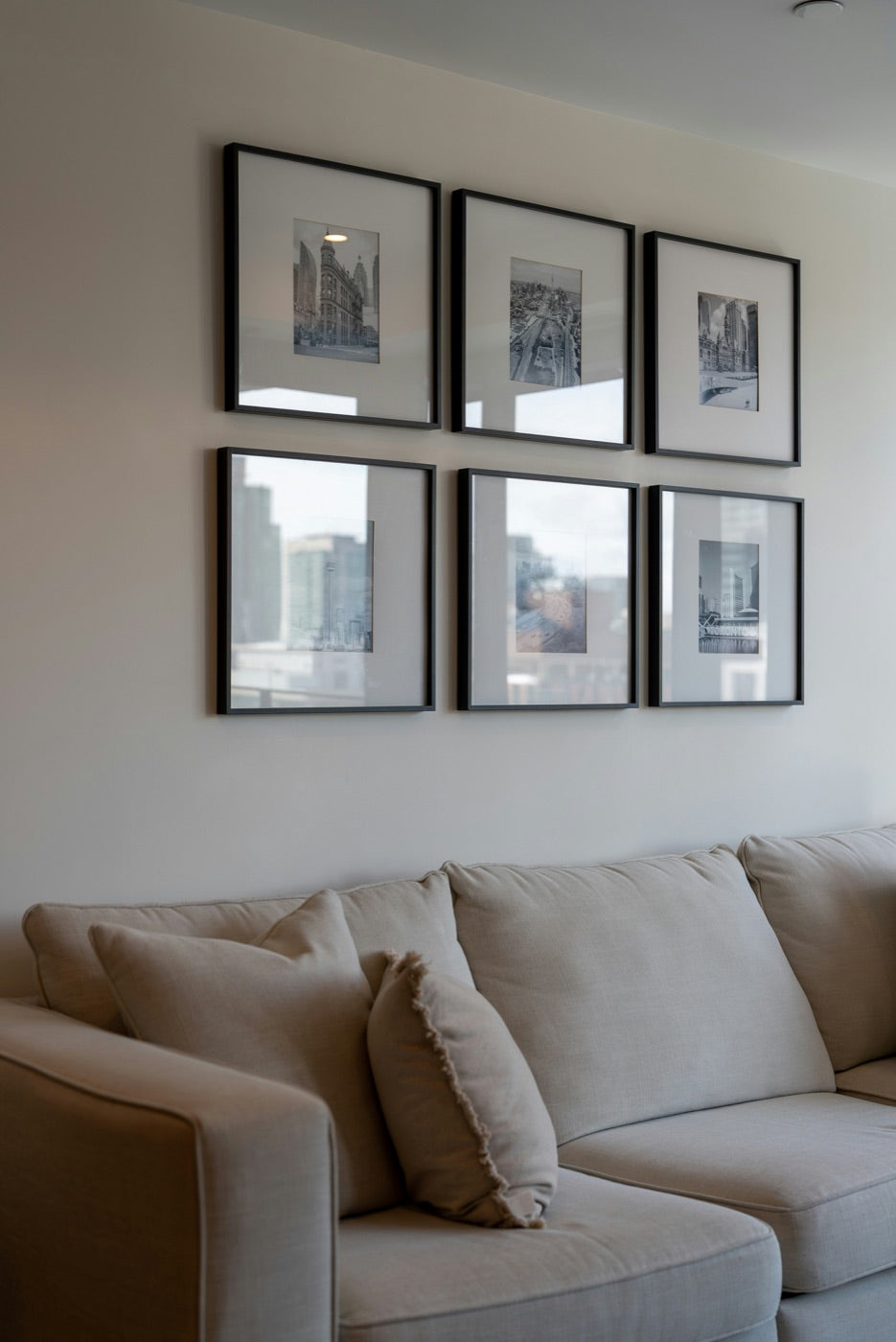 A gallery wall of six matching black frames above a sofa