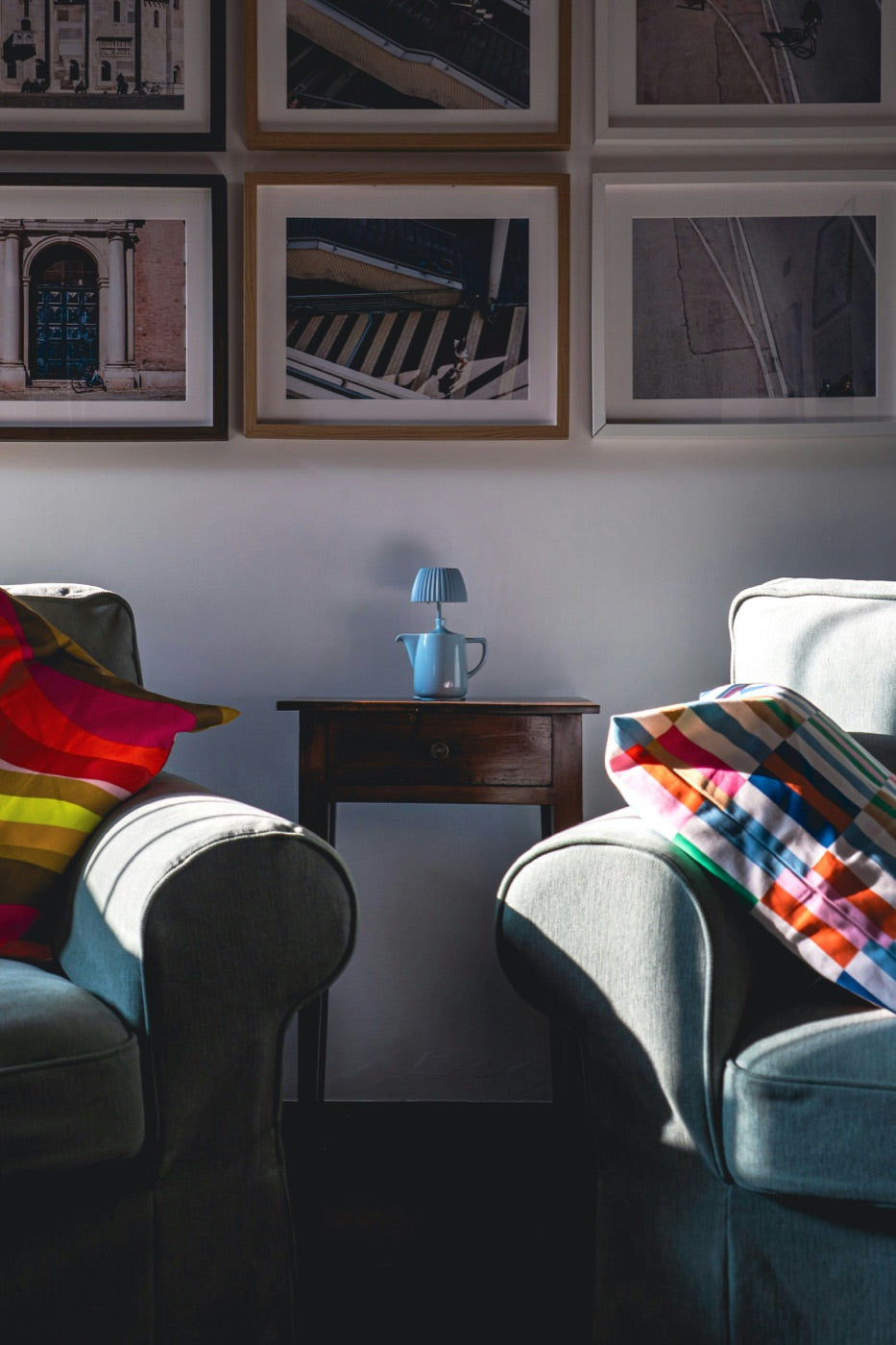 Framed photographs above a pair of armchairs in a sitting room